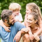 une famille avec 2 enfants dans l'herbe, complicité, communication relationnelle