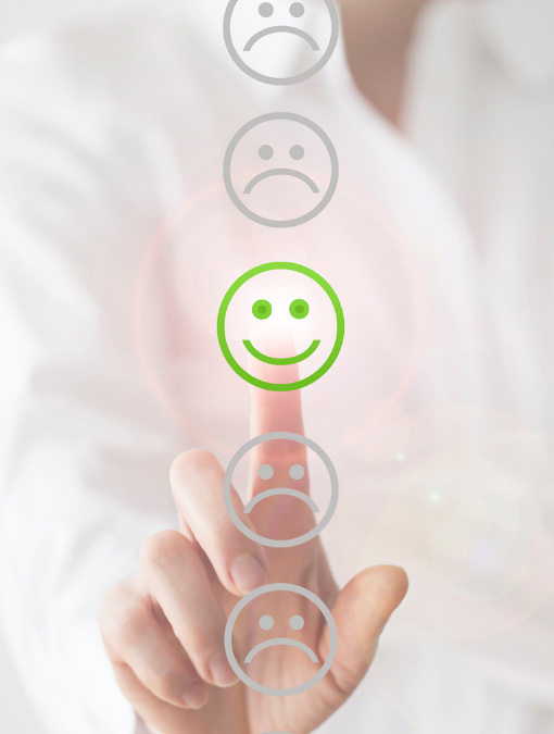 une femme pointe du doigt un smiley content en vers parmi des smiley triste pour indiquer le choix d'une attitude positive avec Emoticoach