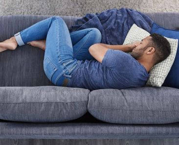 homme blottit sur un canapé ne passe pas à l'action à cause d'un blocage émotionnel