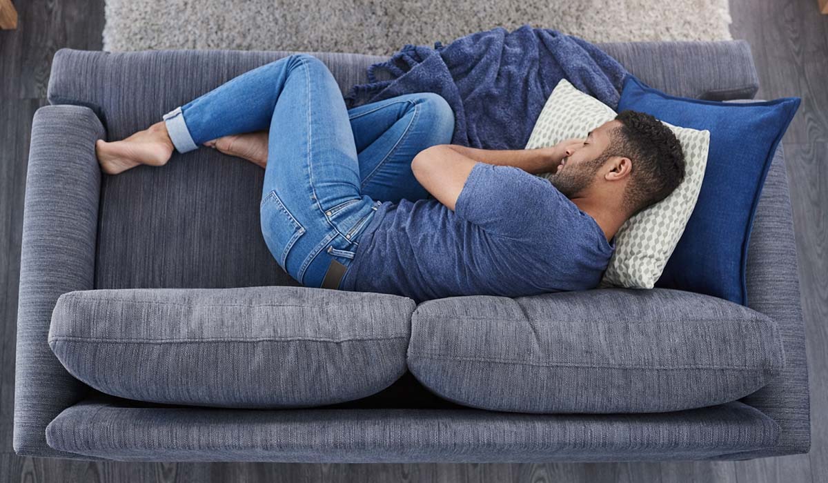 homme blottit sur un canapé ne passe pas à l'action à cause d'un blocage émotionnel