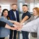 équipe de salariés en entreprise qui s'unissent les mains pour travailler leur cohésion d'équipe grace à un coaching leadership emoticoach